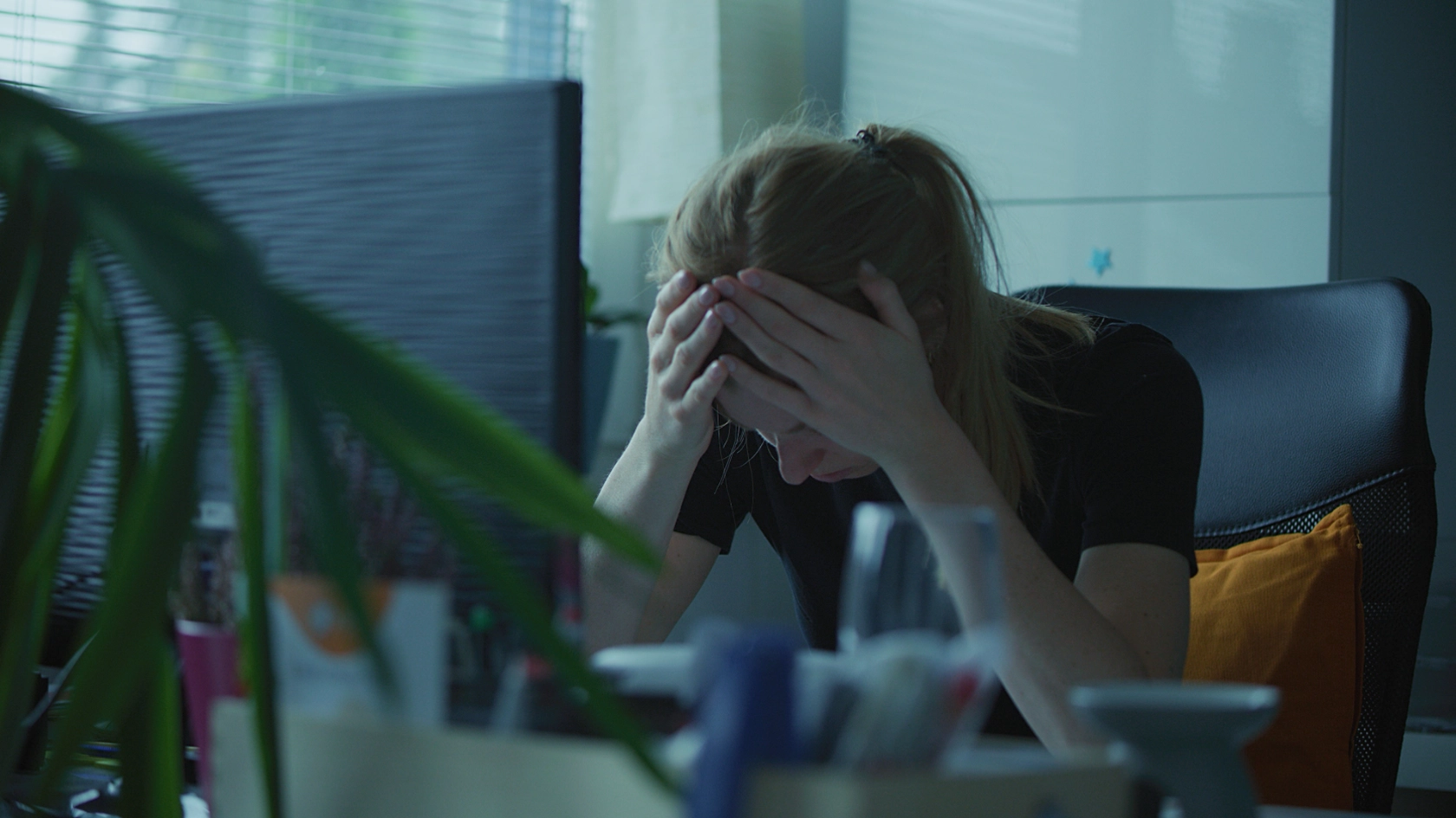 Frau mit gesenkten Kopf an ihrem Schreibtisch im Büro. 